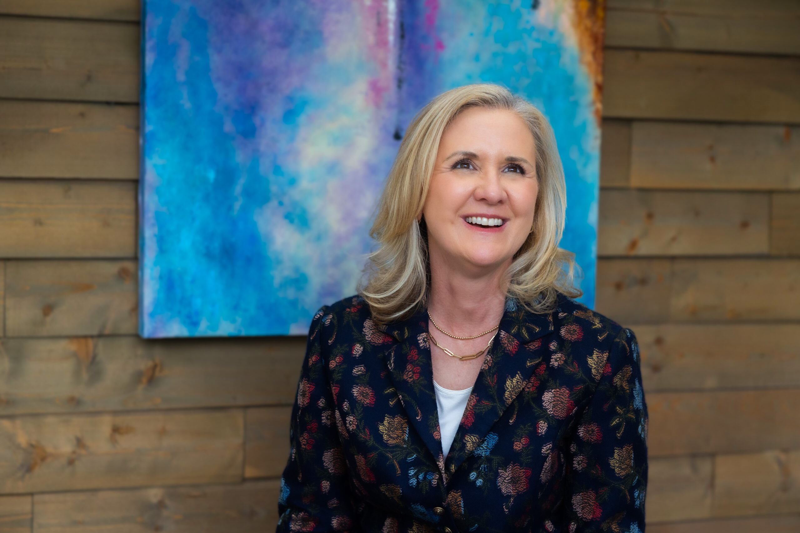 Valerie W Franco Portrait in an office with a colorful background painting.